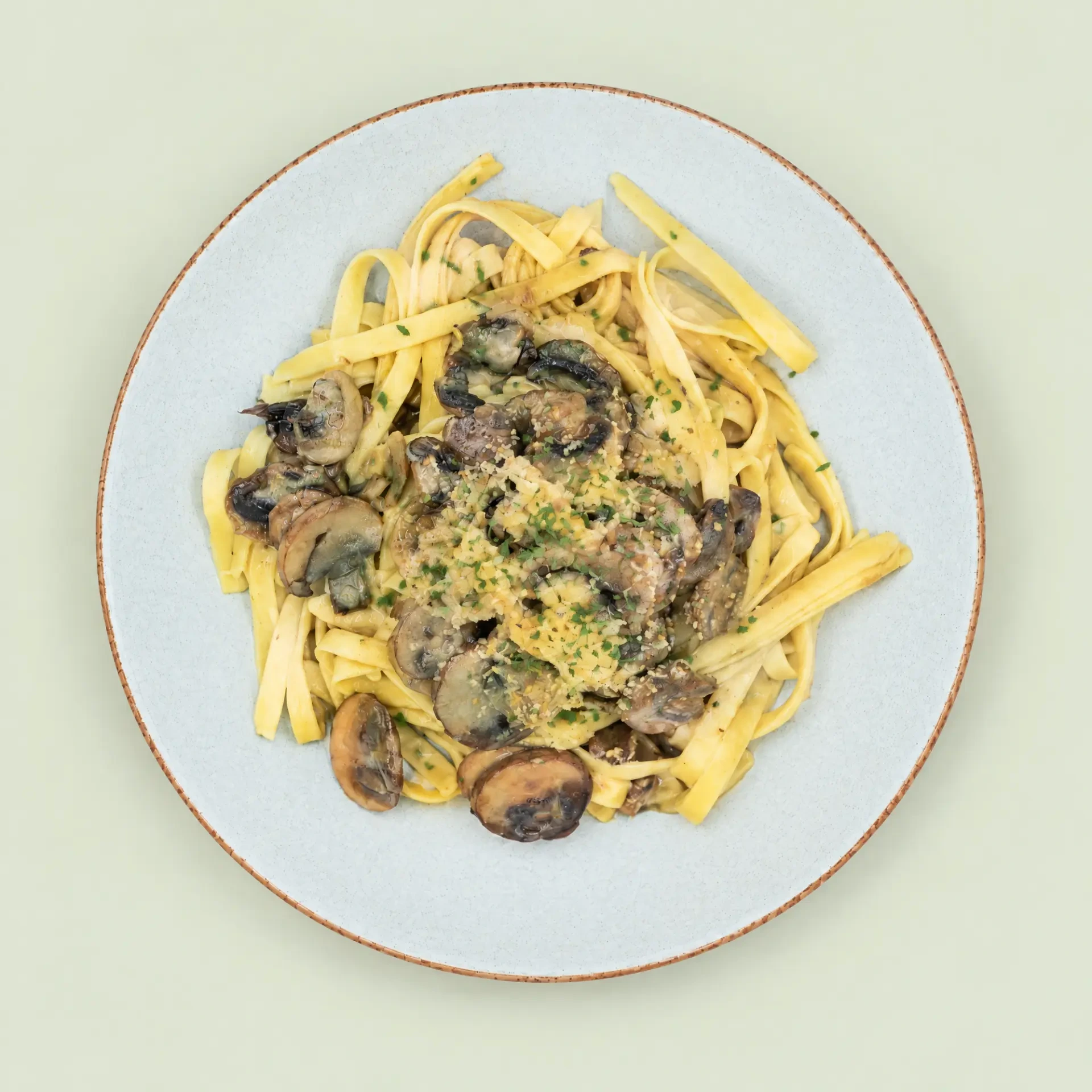 Mushroom Fettuccini with sliced mushrooms and herb garnish on a ceramic plate