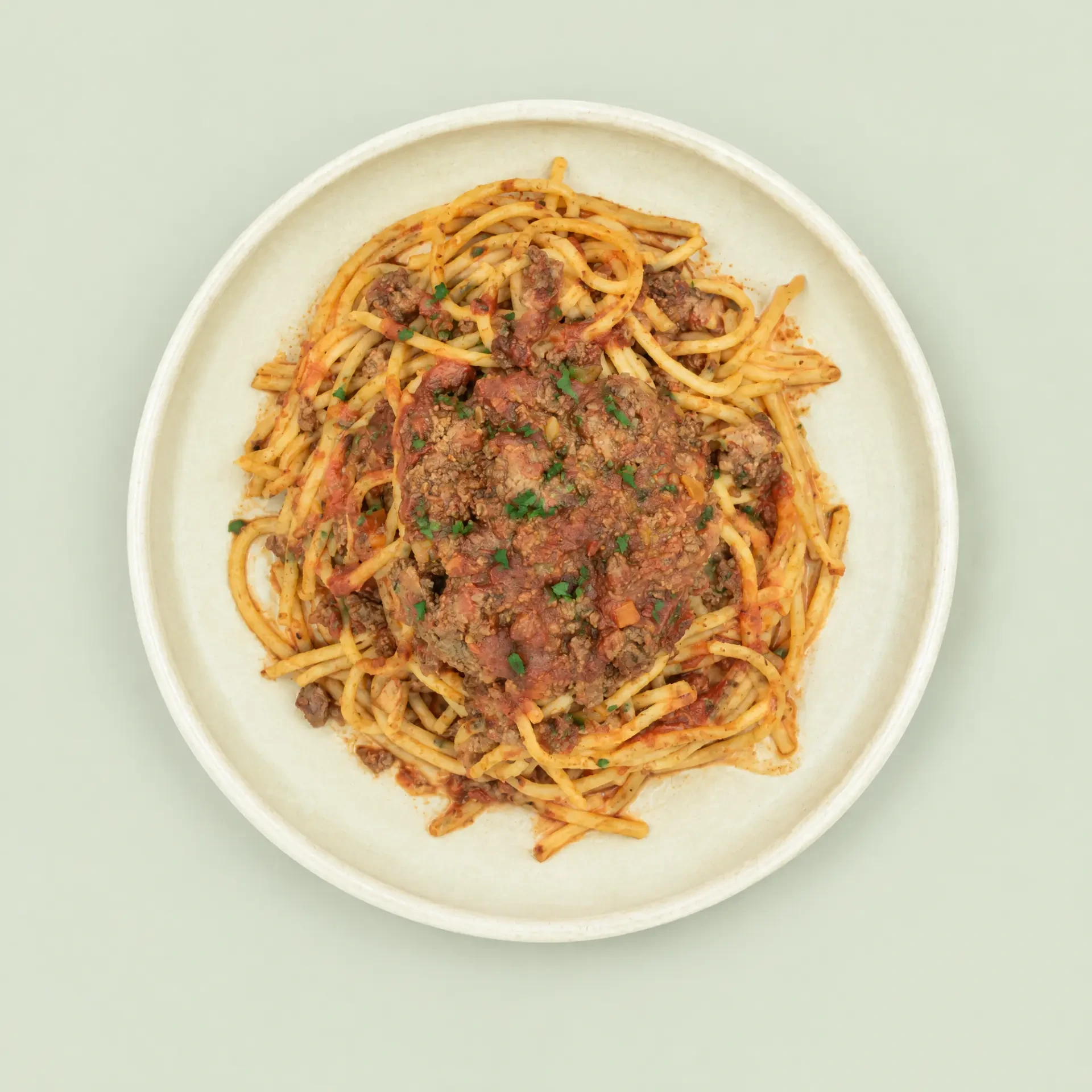 Spaghetti Bolognese with beef sauce and herb garnish on a ceramic plate