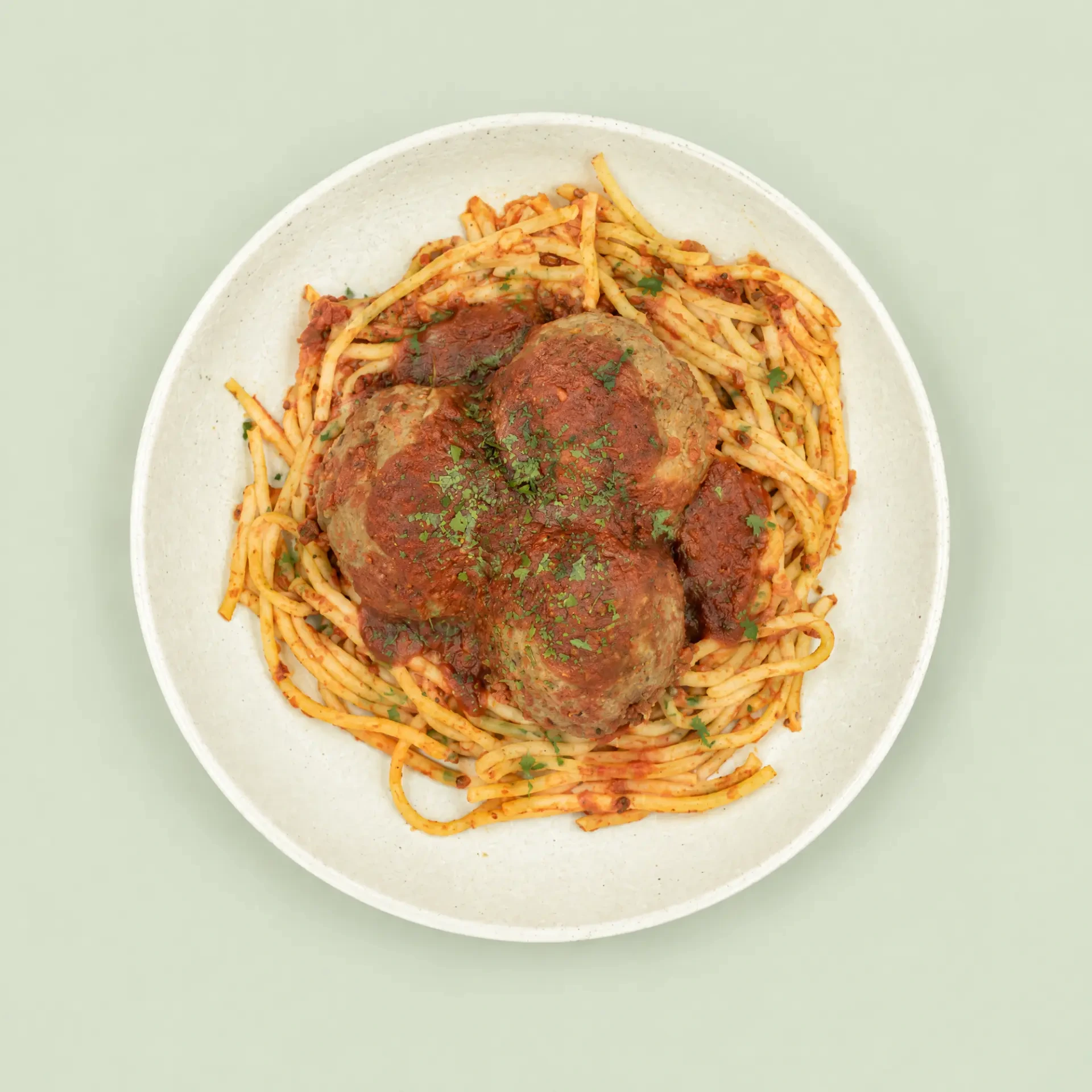 Spaghetti and Meatballs with tomato sauce and herb garnish on a ceramic plate